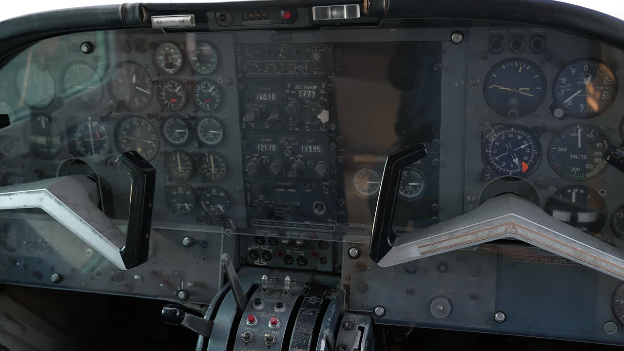 Primo piano della cabina di pilotaggio di un aereo d'epoca con indicatori analogici e cloche di comando.