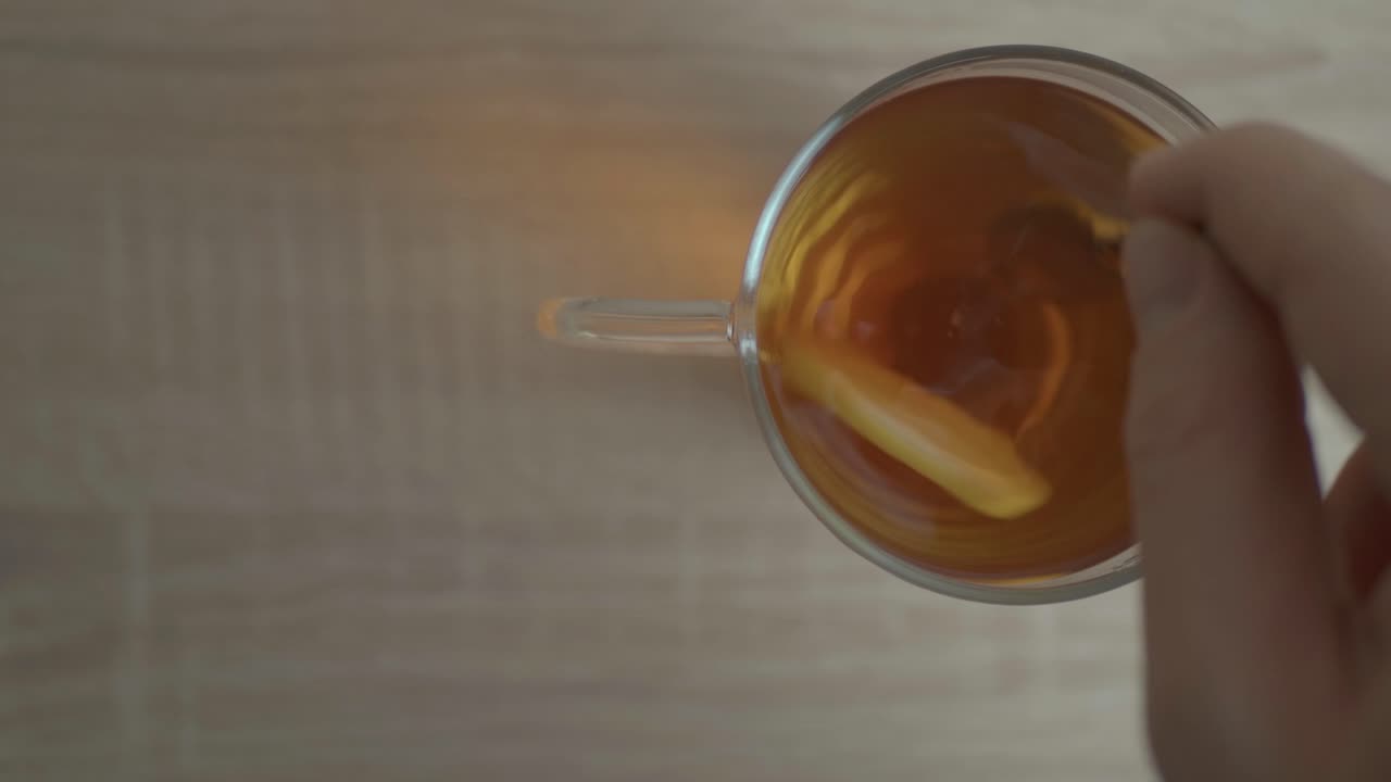 The Aroma Of A Delicious Honey Lemon Tea In A Cup Stirred Clockwise To Blend Its Taste - Close Up Shot