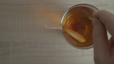 the aroma of a delicious honey lemon tea in a cup stirred clockwise to blend its taste - close up shot