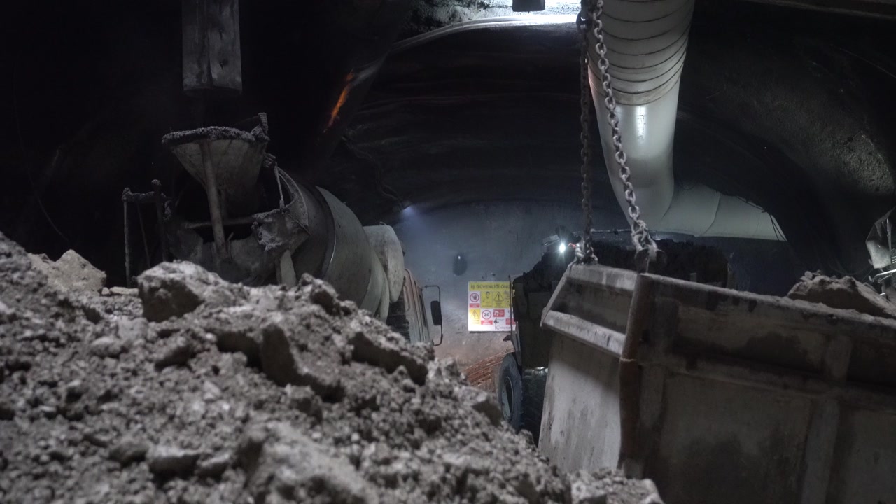 The process of filling the crane bucket with excavation material removed by an excavator in an underground tunnel project to be carried to the surface via a shaft. Heavy industry.