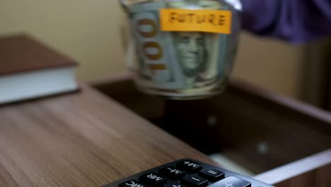 caucasian male putting a glass jar put in a drawer  table with his savings for future