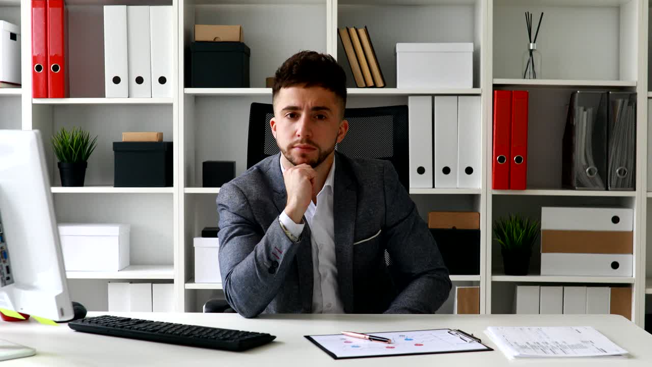 director sentado en la mesa en la oficina blanca y poniendo la mano en la frente.