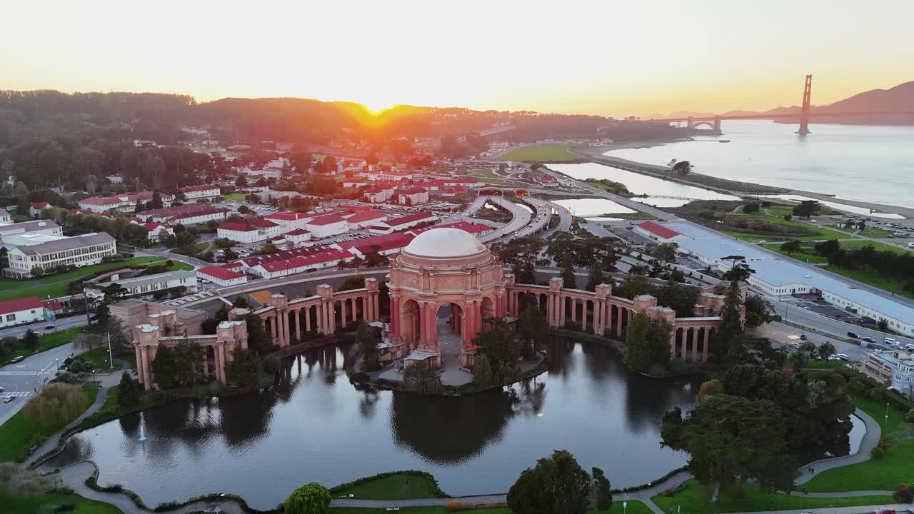 Drone pullaway dronie from the Palace of Fine Arts in San Francisco, revealing the dome, lagoon, and cityscape with warm sunset reflections