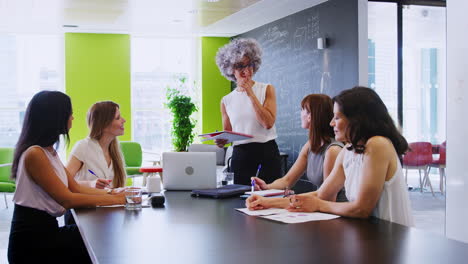 Female-boss-standing-and-talking-at-an-informal-team-meeting