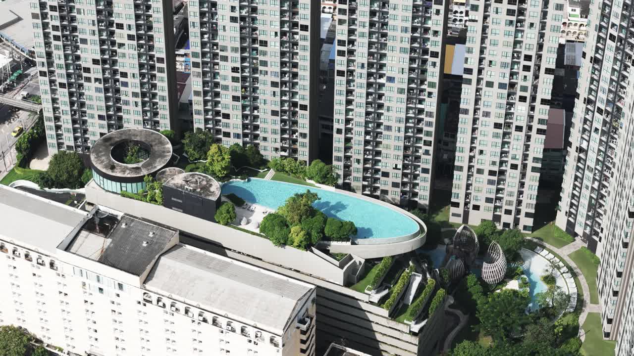 Close up of big oval swimmingpool surrounded by tall buildings