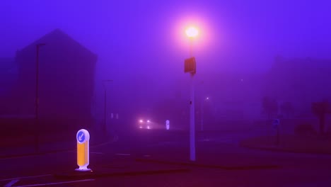 foggy morning in uk. dark purple light. street lights are still on and give off orange glow. car with headlights on is driving down an empty road. man walks with a dog. footage in hd