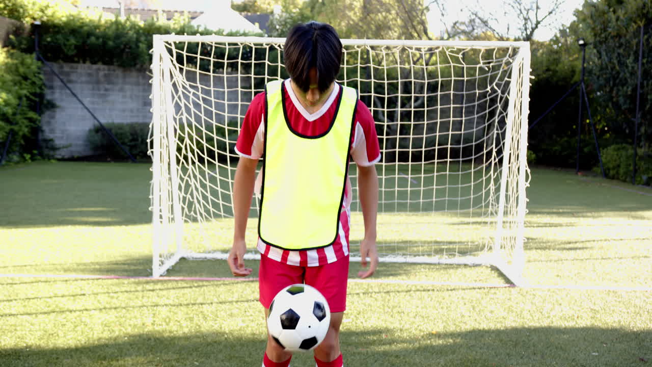Soccer player in red uniform walking on field in front of goal net