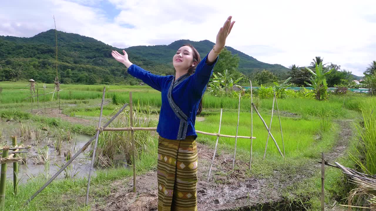 Happy woman in traditional Thai dress in a rice paddy