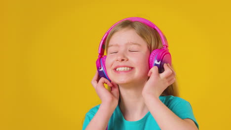 Studio-Portrait-Of-Girl-With-Headphones-Streaming-Music-Against-Yellow-Background