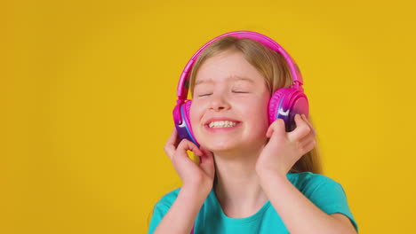 studio portrait of girl with headphones streaming music against yellow background
