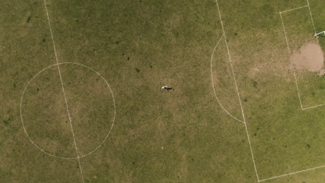 single player practice in middle of local football field, aerial ascend top down view