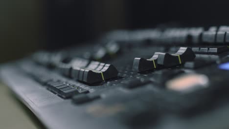 Adjusting-the-light-levels-using-a-lighting-desk-panel-in-a-studio---close-up