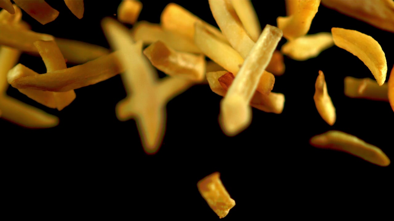 French Fries Falling in Slow Motion Against Black Background