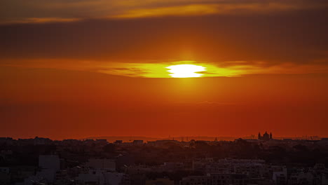 timelapse of golden sun rising across orange sky on calm town