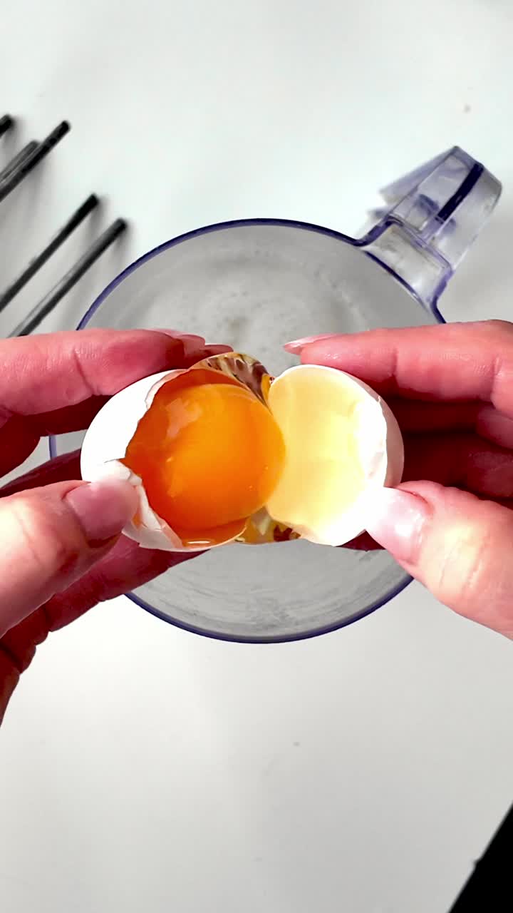 Memisahkan kuning telur dari putih telur ke dalam kendi kaca dalam resep membuat kue rumahan DARI ATAS