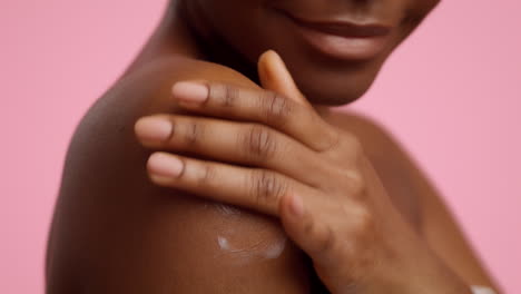 woman applying body lotion to shoulder