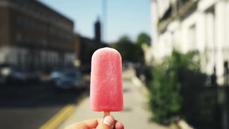 Man-holding-ice-lolly-point-of-view-walking-through-city