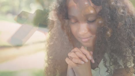 Animation-of-biracial-girl-praying-and-rosary-in-background