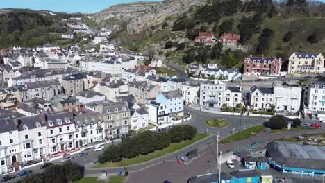 Colourful-Llandudno-seaside-holiday-town-hotels-against-Great-Orme-mountain-aerial-view-slow-push-in
