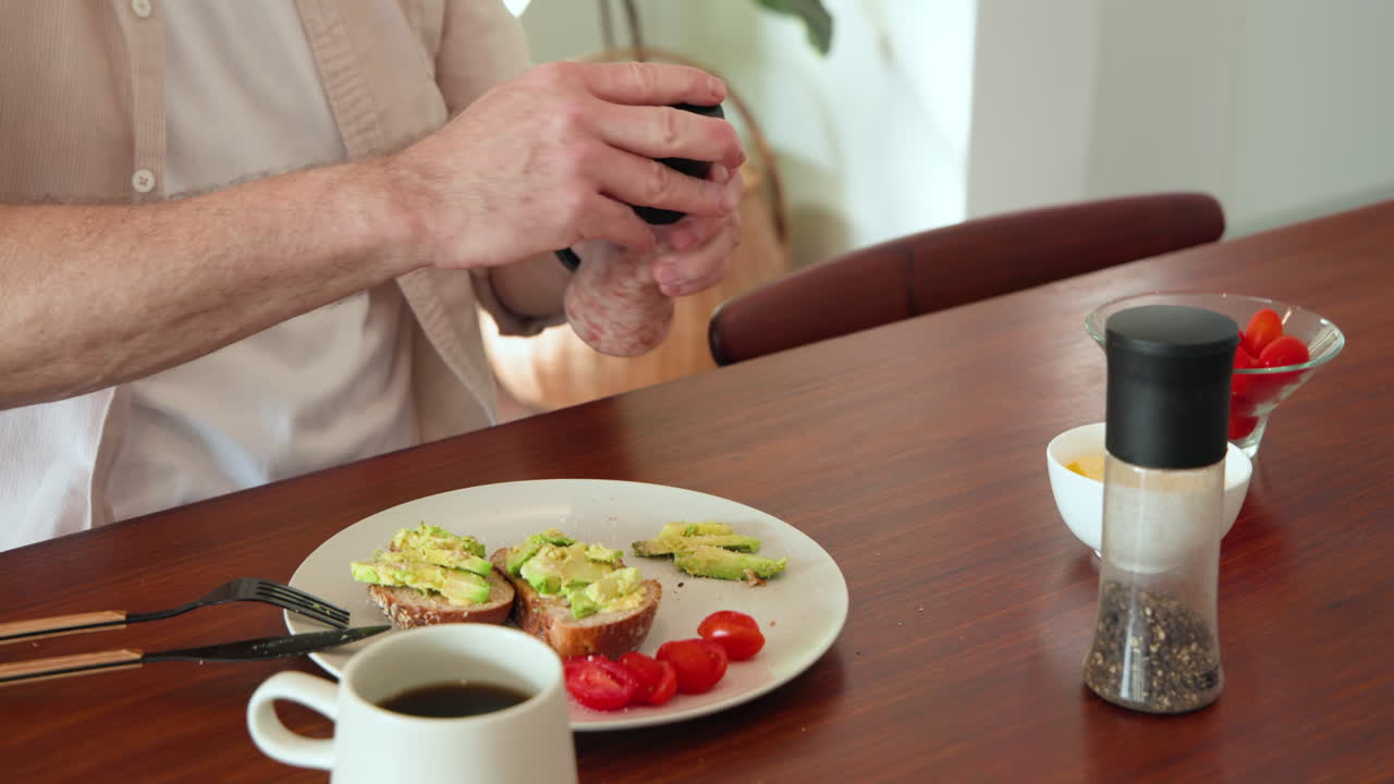 Senior man enjoying avocado toast and coffee at home, preparing for festive breakfast