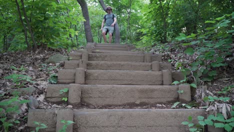 european tourist hiker walks down the wooden stairs following trail path, forest frees background low angle view