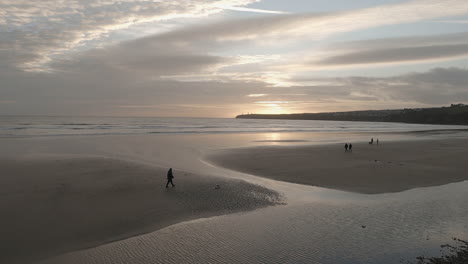 Leute-Gehen-Am-Frühen-Abend-Mit-Hunden-Am-Breiten-Sandstrand-Des-Irischen-Atlantiks-Spazieren