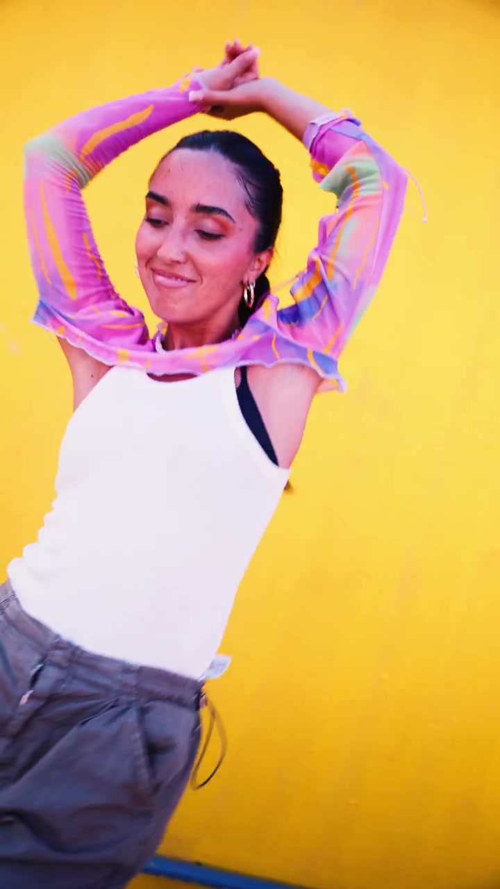 Young Woman Dancing Energetically Against a Bright Yellow Wall