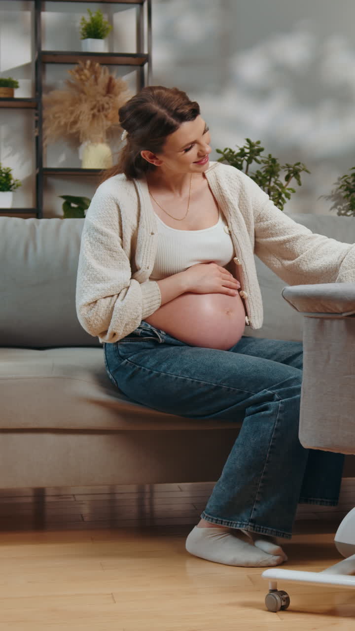 Pregnant woman sits on sofa cradling her belly anticipating motherhood in cozy home environment