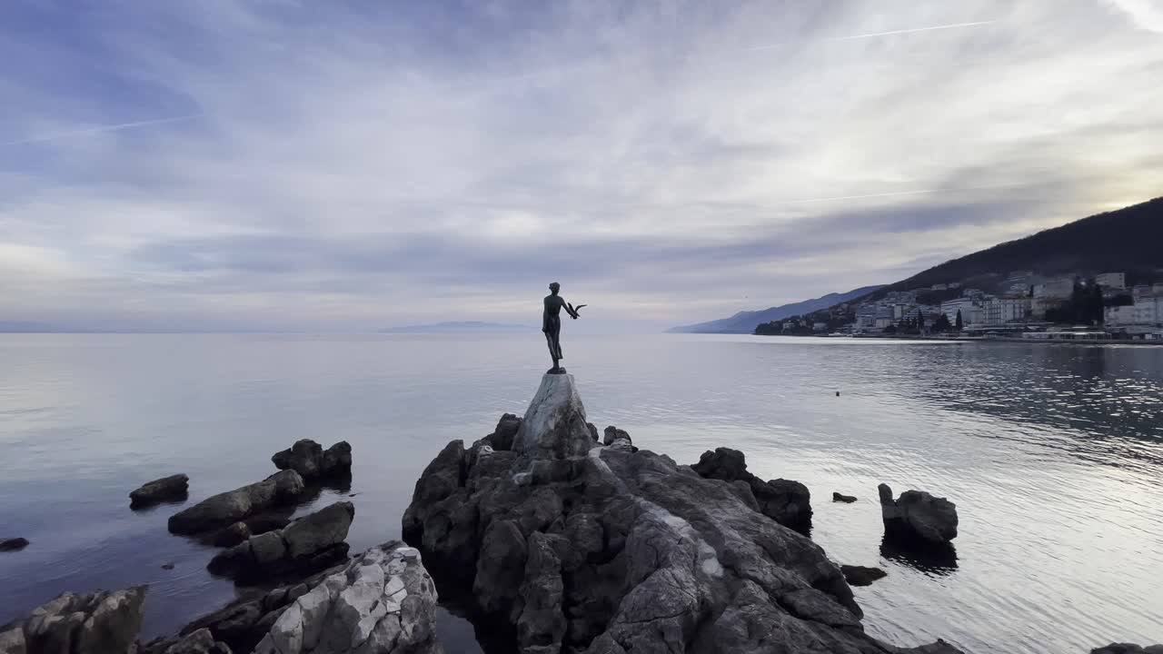 estatua de una mujer en la costa de la ciudad turística de la isla en la distancia de lovran, opatija, croacia