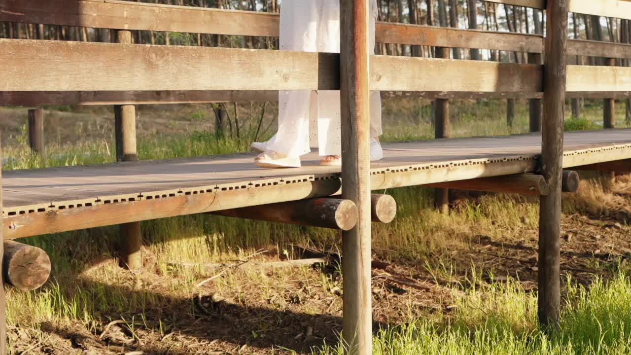 close up of couple’s feet crossing wooden bridge in warm natural evening light