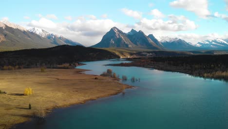 Drone-descent-revealing-turquoise-water-river-at-the-base-of-natural-mountain-valley