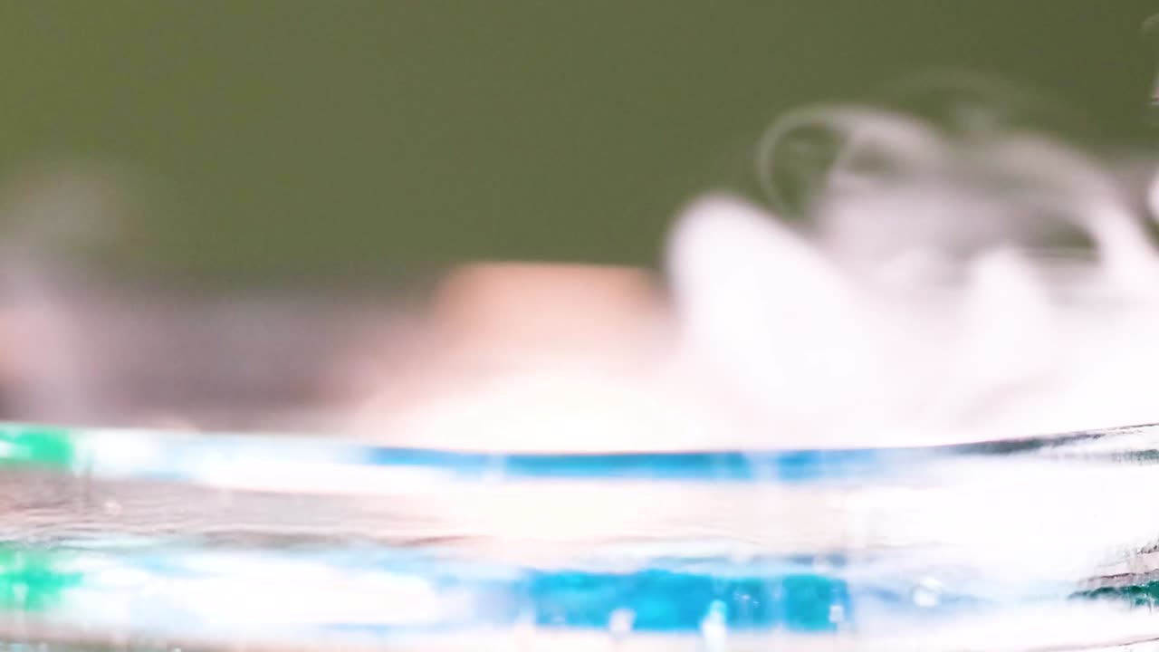 Observe the captivating movement of vapor and colorful liquid in a transparent glass container.