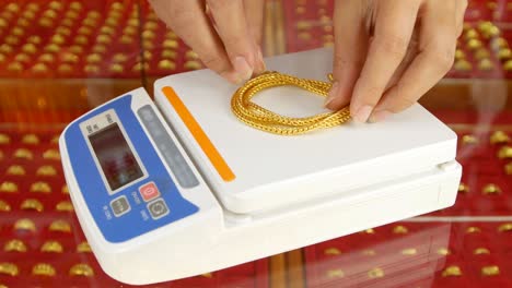 digital scales for weighing gold rings and necklaces with hand in store