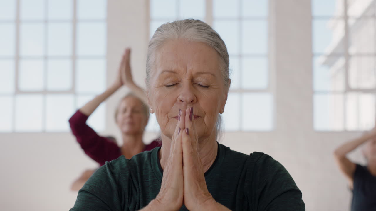 ritratto lezione di yoga bella vecchia donna che esercita una sana meditazione praticando la posa di preghiera godendo di un allenamento di forma fisica di gruppo in studio