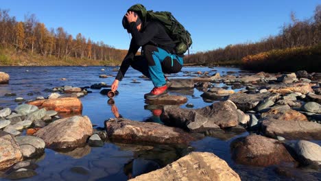 hiker drinking water directly from clean streaming river in northern sweden, lapland, abisko