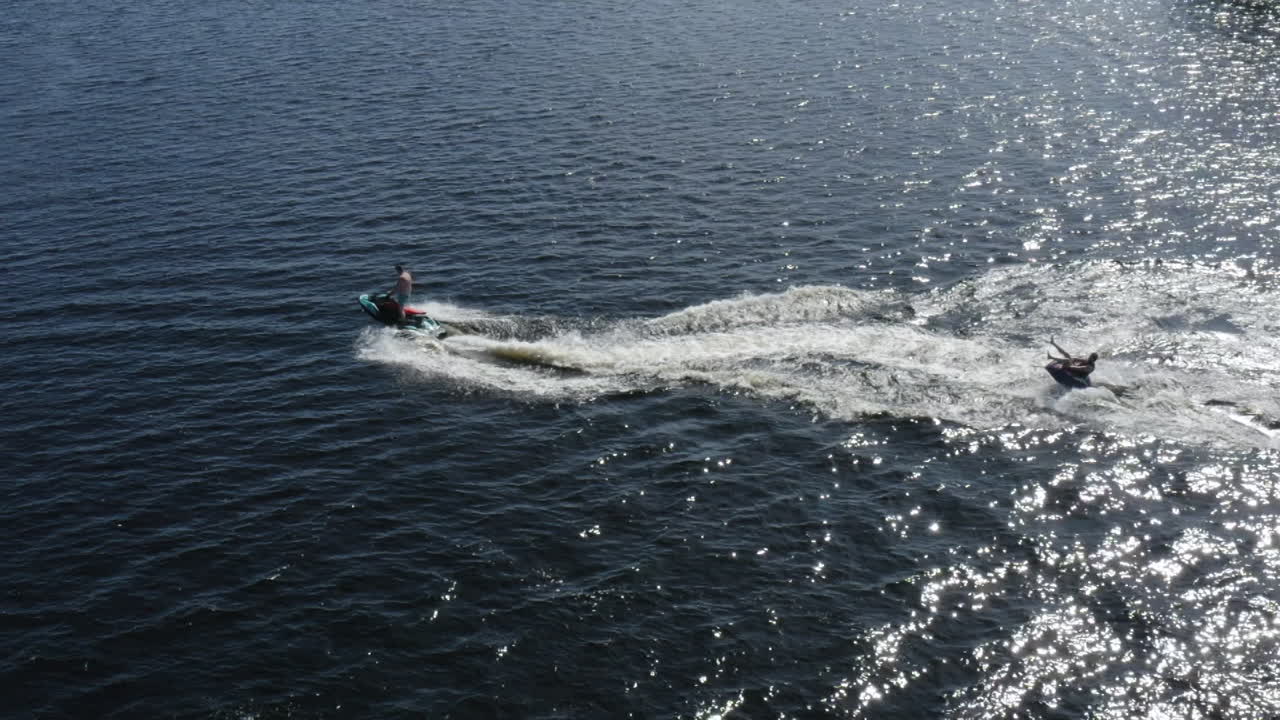 vista aérea de hombres jóvenes disfrutando de la vida mientras montan en un ringo y jet ski en cámara súper lenta