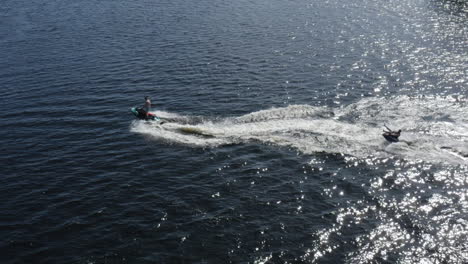 aerial view of young men enjoying life while riding on a ringo and jet ski in super slow motion