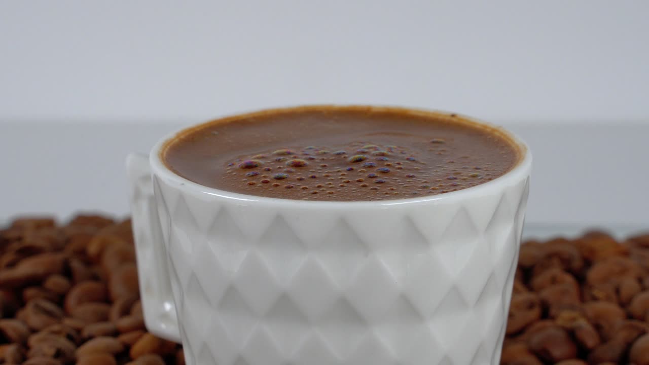 Caffè turco in una tazza bianca circondato da chicchi su uno sfondo pulito