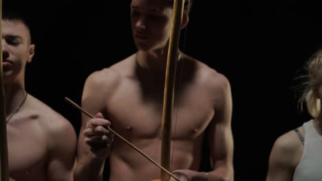 un grupo de bailarines profesionales están practicando capoeira en la oscuridad contra un foco de luz en un fondo negro de estudio. arte marcial afro-brasileño que combina elementos de la danza.