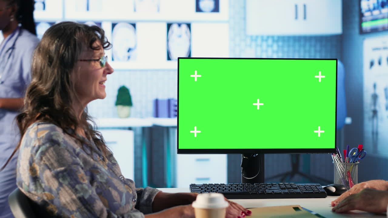 Old general practitioner discusses with female patient next to green screen