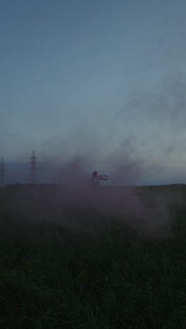 mujer en un campo al anochecer con humo de colores