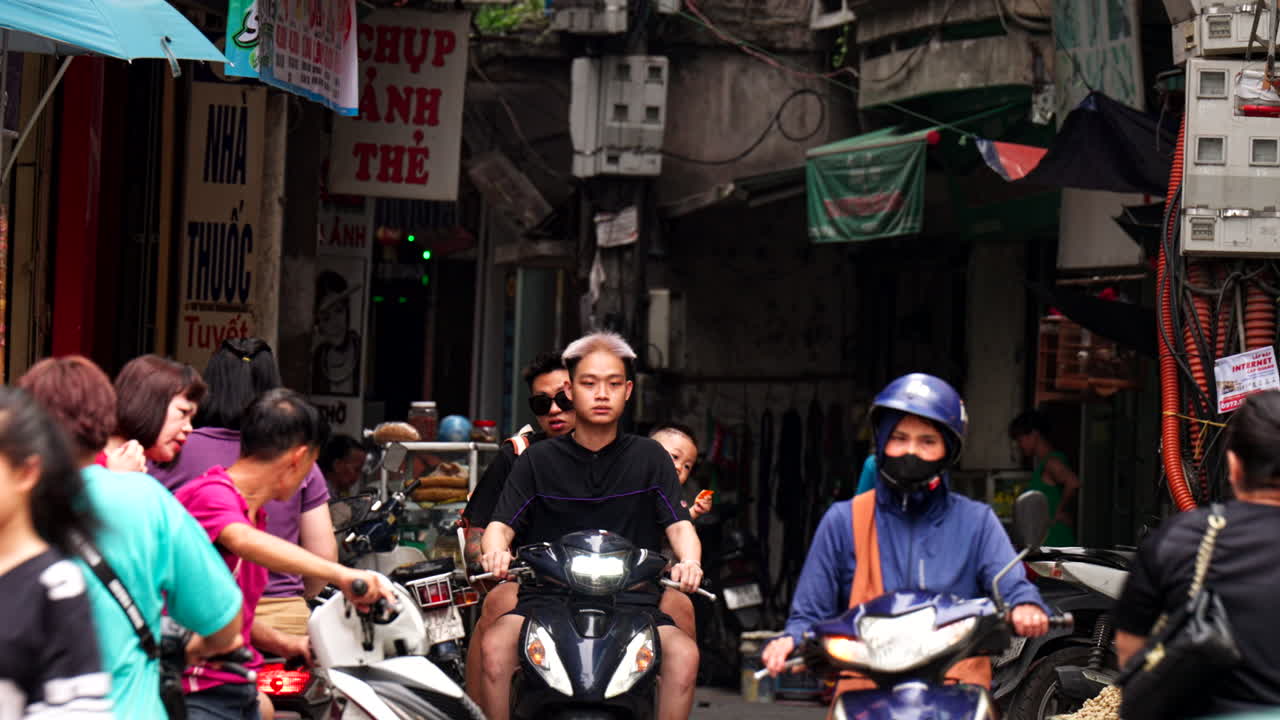Local Hanoi residents driving two-wheelers in the narrow streets of city