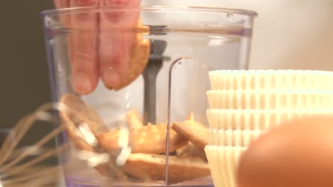 rompiendo galletas para hacer base de tarta de queso triturando