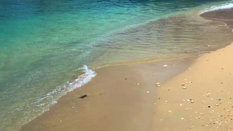 Water-lapping-the-sandy-shoreline,-of-this-peaceful-beach-ins-slow-motion