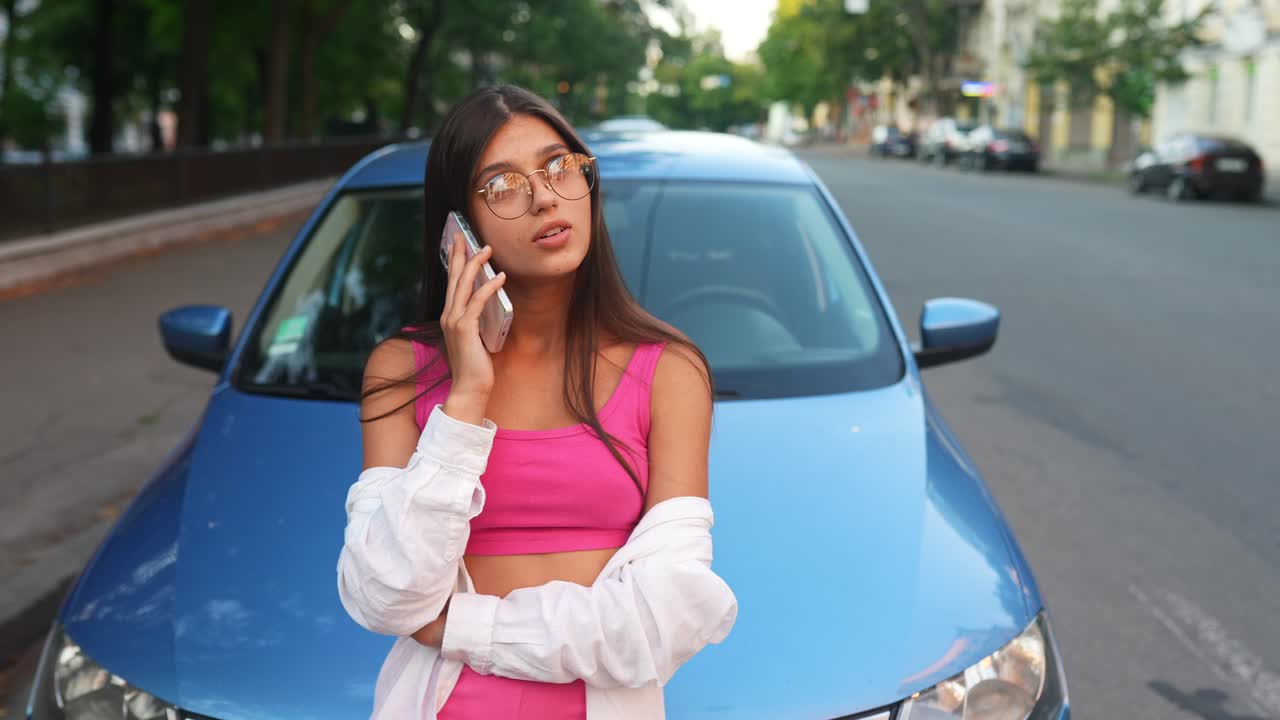 joven en el teléfono cerca de un coche azul