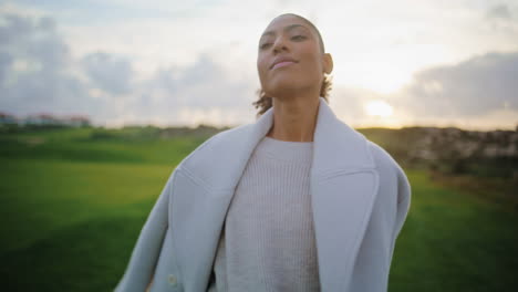 closeup happy woman spinning on cloudy sunset. serene black hair girl close eyes