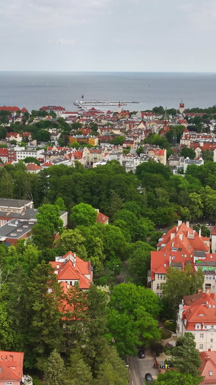Vertical drone shot over red rooftops and urban trees in downtown Sopot, Poland