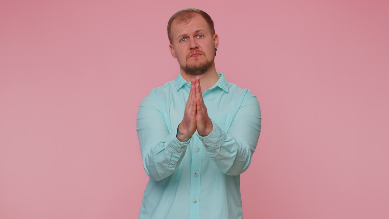 Trendy young adult man praying looking upward and making wish asking god for help begging apology