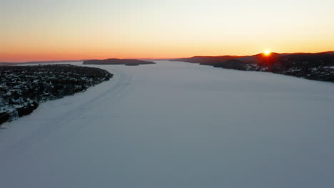 scenic aerial view flying over a frozen river at sunset