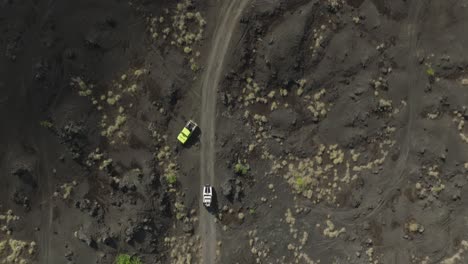 vehículo jeep 4x4 conduciendo a través de un paisaje de arena volcánica seca, aéreo